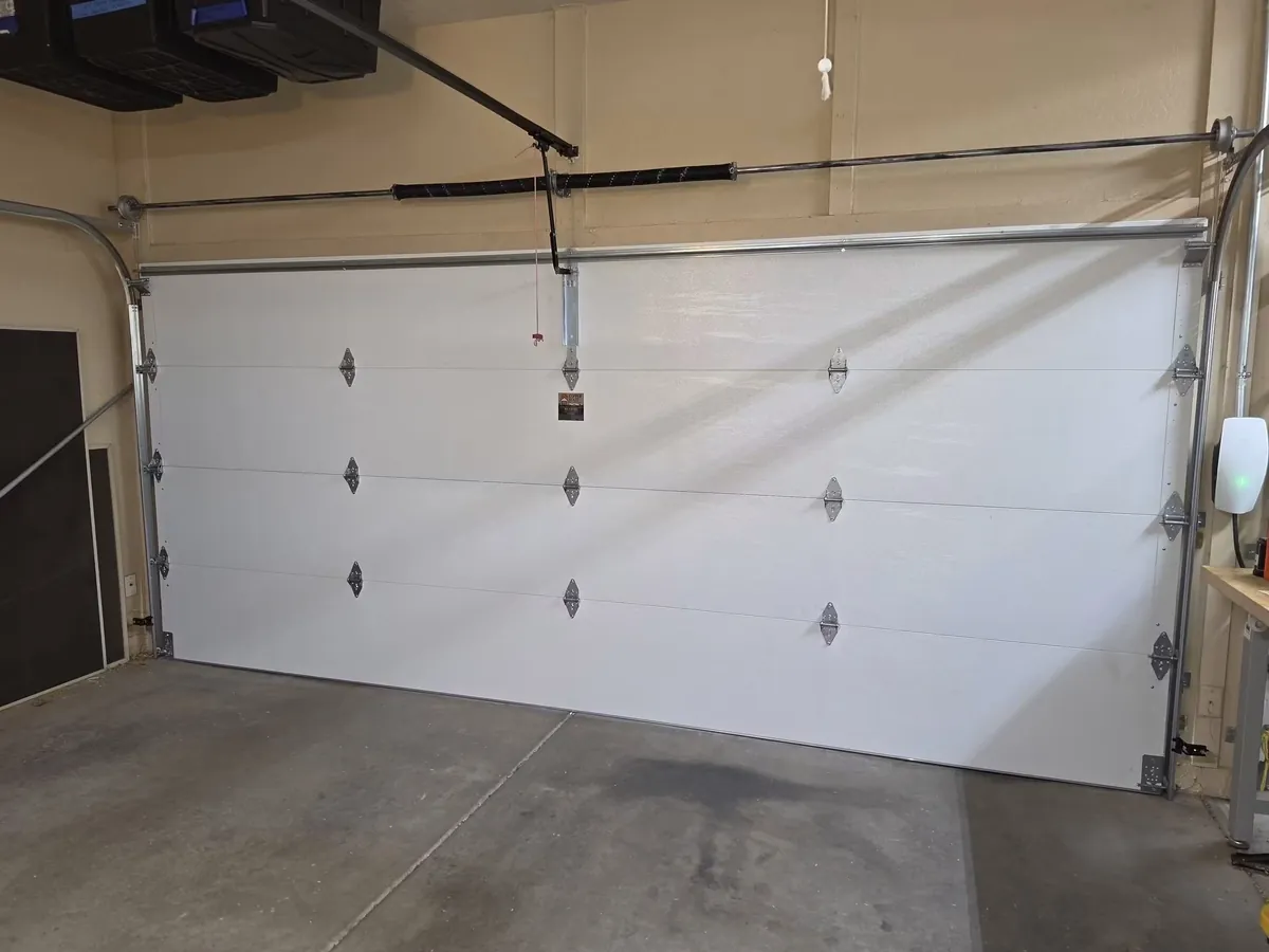 Interior of a white sectional garage door showing hinges, tracks and a two-spring system